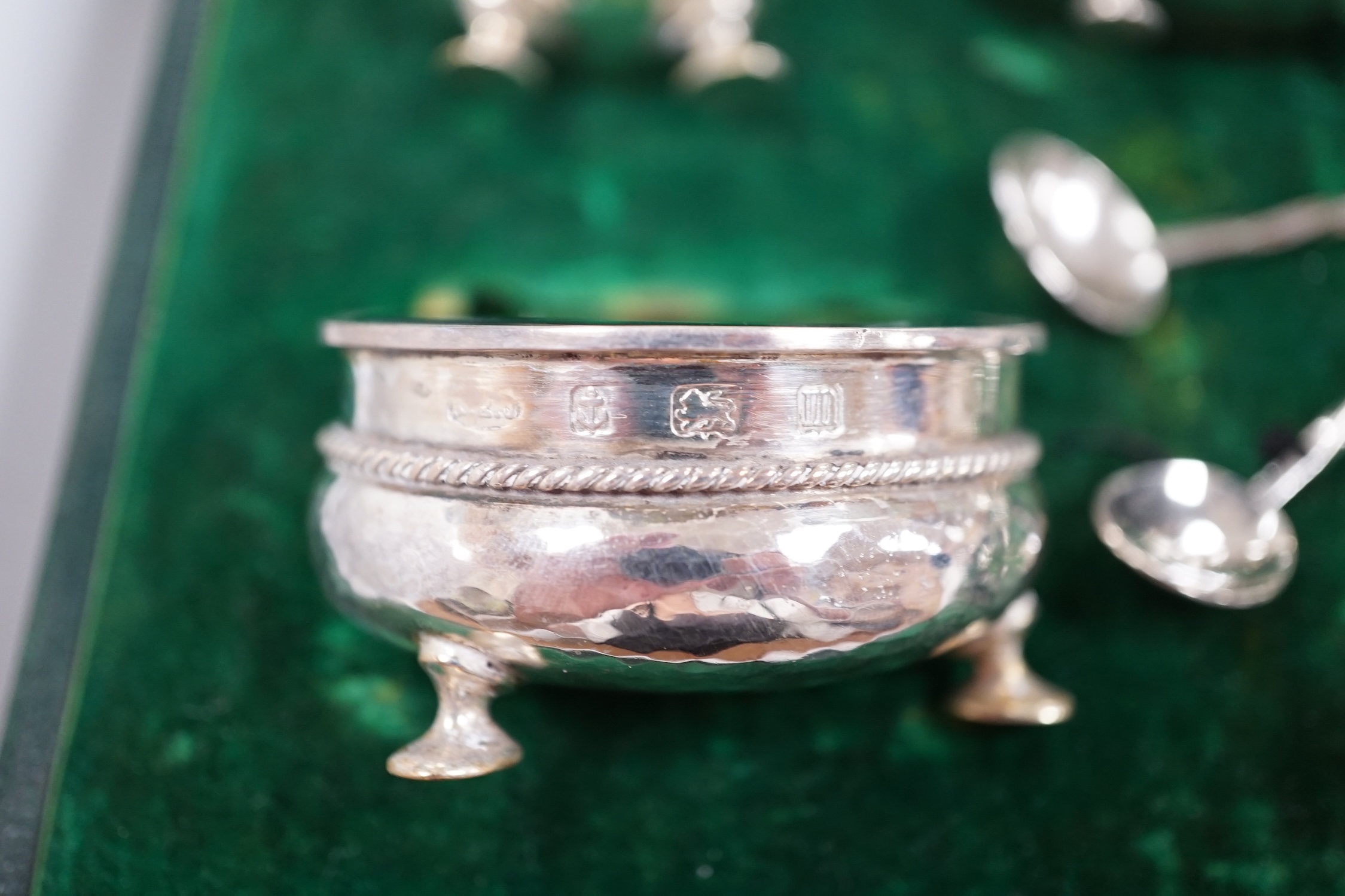 A cased George V planished silver five piece condiment set and three matching spoons by A.E. Jones, Birmingham, 1911.